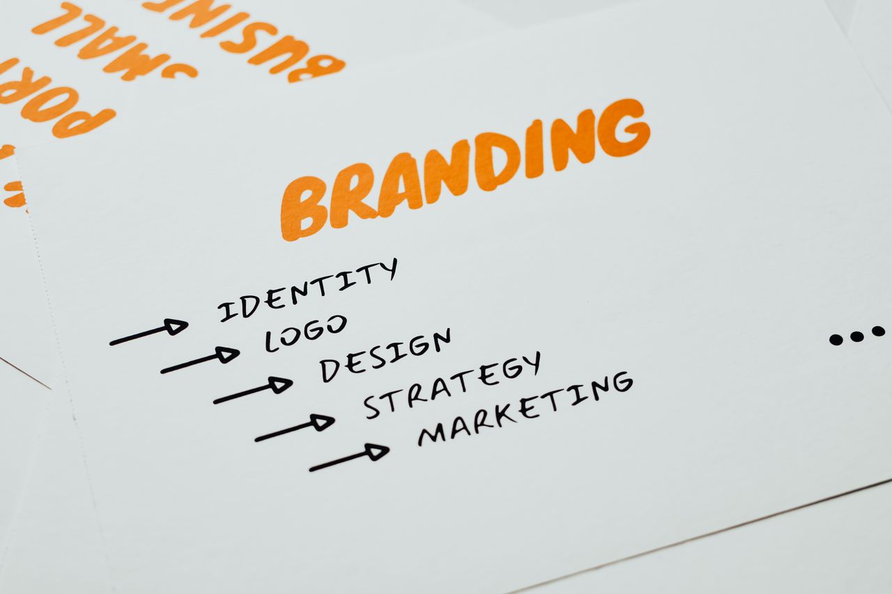 services-04 Close-up of a paper with branding, identity, design, strategy, and marketing concepts in orange and black.