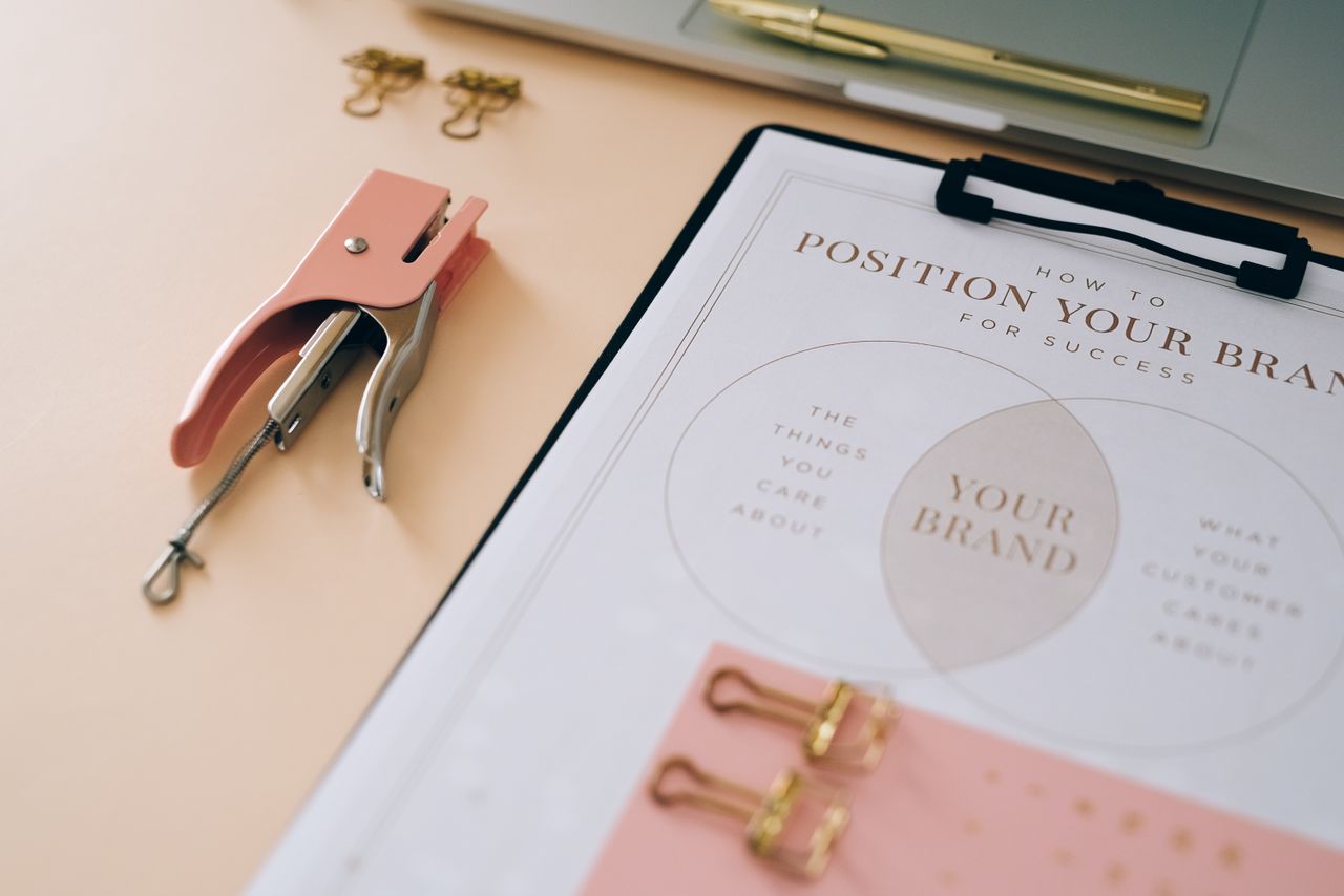 services-02 Pink stapler and branding document on a desk showcasing stylish office setup.